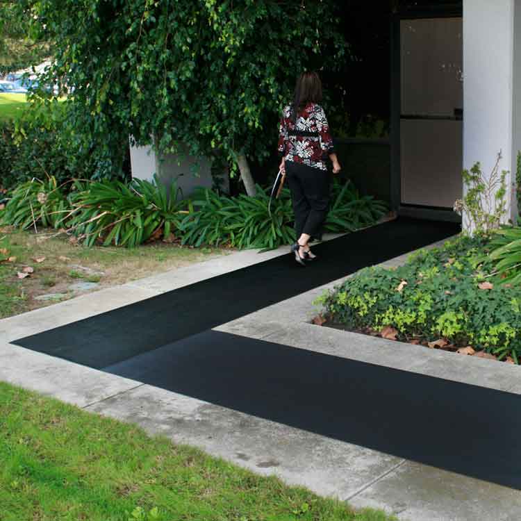 Fine_Rib_Action6_Large Woman walking to a door entrance lined with black corrugated fine rib rubber runner mats