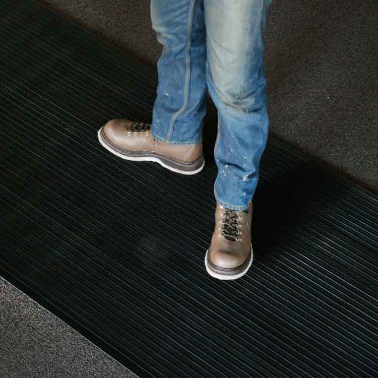 Composite_Rib_Action2_Angle1_Large Black Color Rubber Runner Mats with Extra Toehold in Wet Conditions a person standing