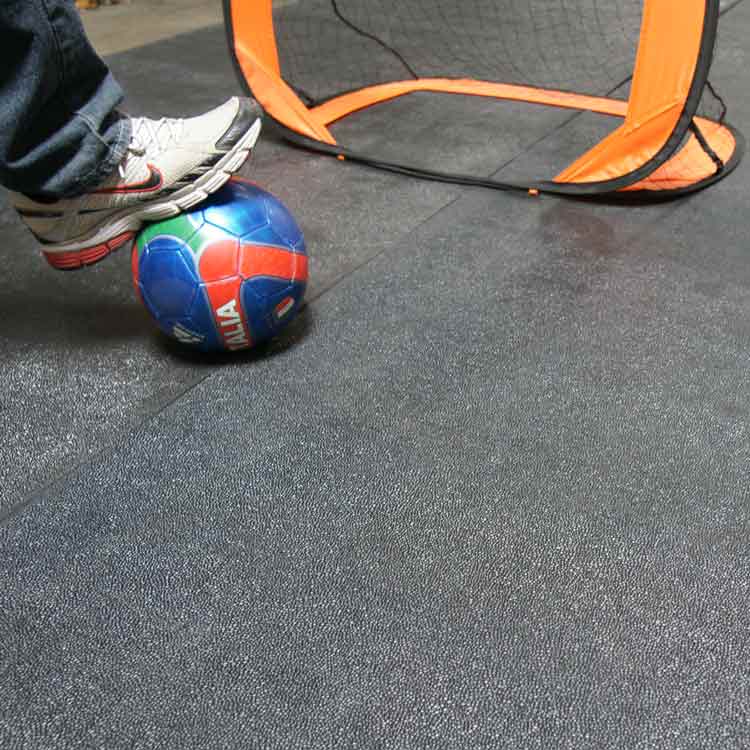 Tuff_N_Lastic_Action_Shot_3A_Large Black color Reclaimed Safety Rubber Mat Improves Traction and Resilience man standing playing with ball